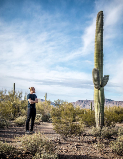Man standing next to very tall cactus