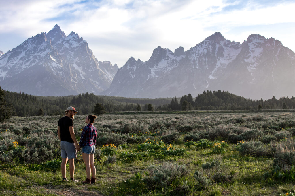 two people standing outside next to the mountains